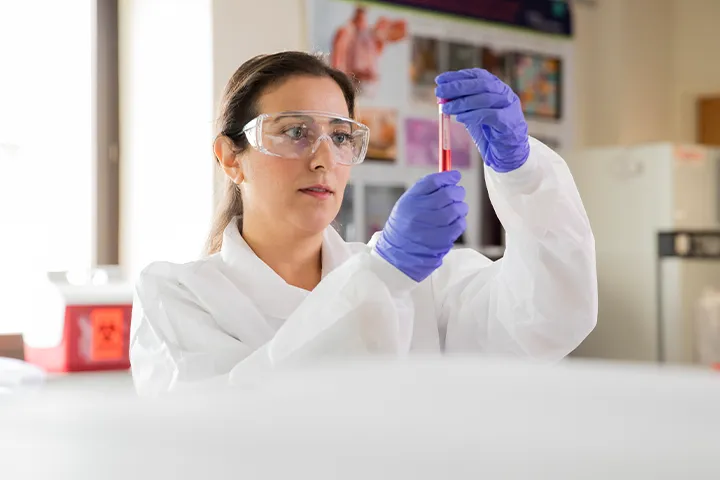 Individual wearing protective wear holding a tube