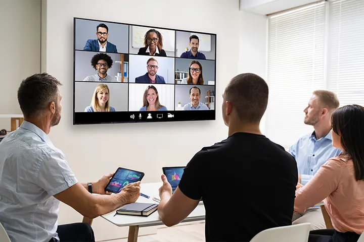Group of people looking at a screen with people on it